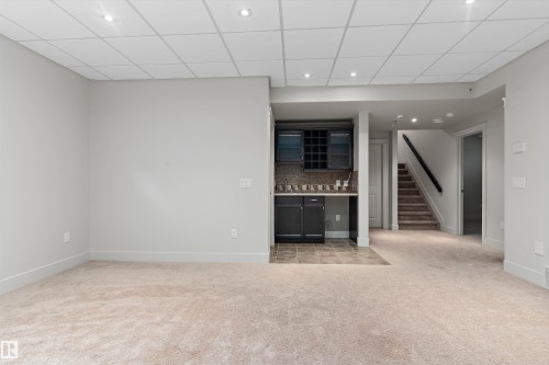 Recessed lighting, drop ceiling, built-in wet bar with cabinetry, tile backsplash, and carpeted flooring - 17535 110 Street Nw, Edmonton, AB 