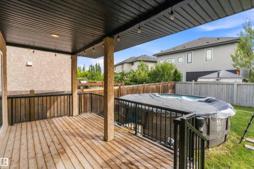 Covered outdoor deck with wood-finish flooring, black metal railings, and string lighting - 17535 110 Street Nw, Edmonton, AB 