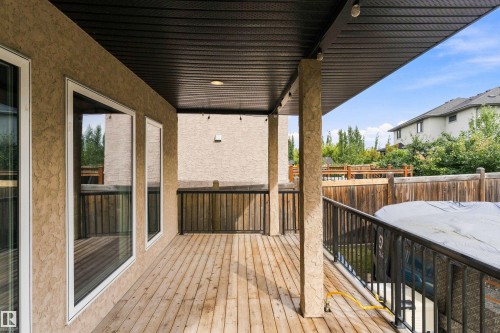 Covered wood-plank deck with dark metal railings, stucco exterior, and recessed lighting - 17535 110 Street Nw, Edmonton, AB 