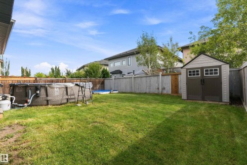 Expansive backyard featuring a green lawn, wood fencing, and a detached storage shed - 17535 110 Street Nw, Edmonton, AB 