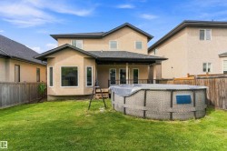 Expansive backyard with a manicured lawn, an above-ground pool, and a covered patio area - 
