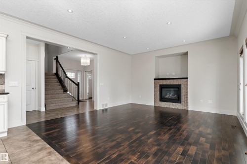Rich wood-finish flooring, recessed lighting, and a fireplace with a decorative tile surround and dark mantel - 17535 110 Street Nw, Edmonton, AB 