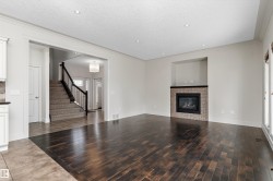 Rich wood-finish flooring, recessed lighting, and a fireplace with a decorative tile surround and dark mantel - 