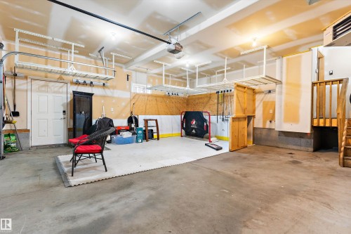 Concrete flooring, built-in overhead storage racks, interior access door, wood staircase, and wood-paneled walls - 17535 110 Street Nw, Edmonton, AB 
