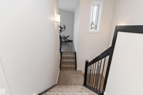 Carpeted staircase featuring black railings and white walls - 17535 110 Street Nw, Edmonton, AB 