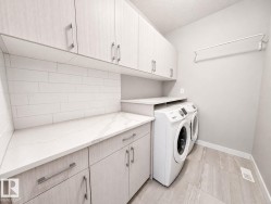 Full-size washer and dryer, tile flooring, solid surface countertops, extensive upper and lower cabinetry, and subway tile backsplash - 