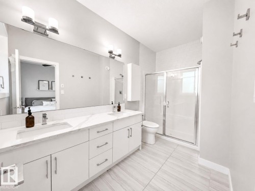 Dual vanity with integrated sinks, quartz-finish countertop, and full-width mirror - 10516 76 Street Nw, Edmonton, AB 