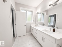 Dual vanity with integrated sinks and white countertops, under-vanity storage, large wall-mounted mirror, and tile flooring - 