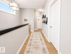 Wood-finish flooring, contemporary light fixture, modern white doors, minimalist wall shelving, and a horizontal transom window - 