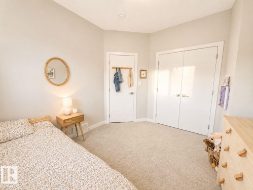 Plush carpeting, a built-in closet with double doors, and a wood-finish dresser with unique hardware - 10516 76 Street Nw, Edmonton, AB 