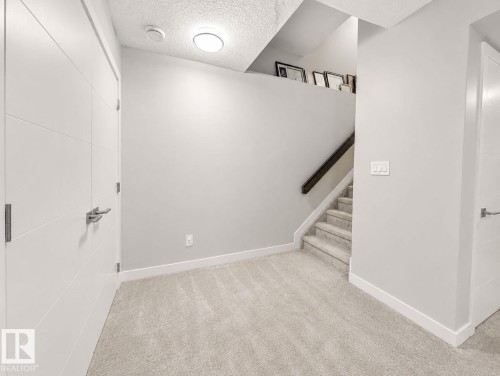 Carpeted flooring, recessed ceiling lighting, light gray wall finishes, modern panel doors, and a wood-finish handrail - 10516 76 Street Nw, Edmonton, AB 