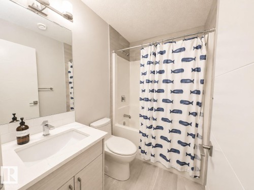 White vanity with a single basin sink, chrome faucet, and integrated countertop - 10516 76 Street Nw, Edmonton, AB 