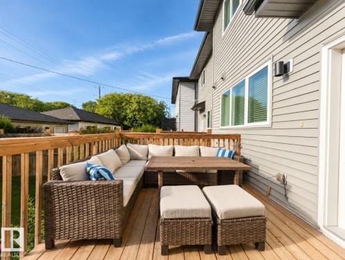Expansive wood-finish deck with wood railings, multiple windows, and exterior wall lighting - 10516 76 Street Nw, Edmonton, AB 