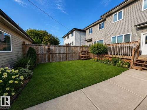 Manicured lawn with perimeter landscaping, wood fencing, a wooden deck, and concrete hardscaping - 10516 76 Street Nw, Edmonton, AB 