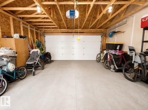 Attached garage with exposed wood ceiling beams, overhead lighting, and a neutral concrete floor - 10516 76 Street Nw, Edmonton, AB 