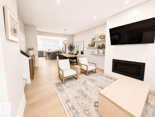 Open-concept living space featuring wood-finish flooring, recessed lighting, and a linear electric fireplace - 10516 76 Street Nw, Edmonton, AB 