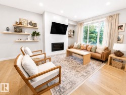 Recessed lighting illuminates the open living area featuring wood-finish flooring, a built-in fireplace, and expansive windows - 