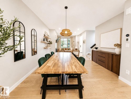 Open-concept dining area featuring wood-finish flooring, a contemporary pendant light fixture, and a built-in wood-tone credenza - 10516 76 Street Nw, Edmonton, AB 