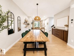 Open-concept dining area featuring wood-finish flooring, a contemporary pendant light fixture, and a built-in wood-tone credenza - 