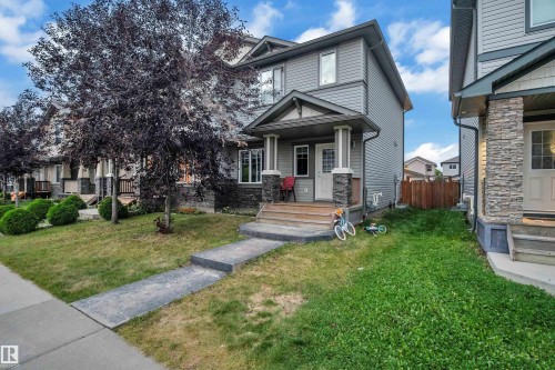 Exterior featuring gray siding, stone accent columns, a covered porch, and a concrete walkway - 1491 33B Street Nw, Edmonton, AB 