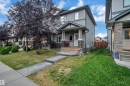 Exterior featuring gray siding, stone accent columns, a covered porch, and a concrete walkway - 1491 33B Street Nw, Edmonton, AB 