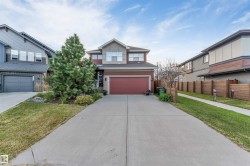 Two-story property with a double-width concrete driveway, attached front garage, and natural wood privacy fencing - 