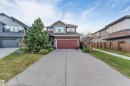 Two-story property with a double-width concrete driveway, attached front garage, and natural wood privacy fencing - 718 Charlesworth Way Sw, Edmonton, AB 