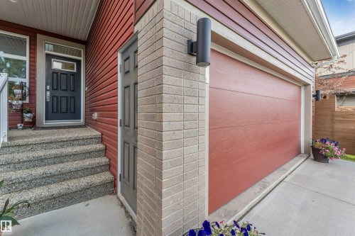 Exterior featuring brick and horizontal siding, an attached garage, a front entry door with transom window, and textured concrete steps - 718 Charlesworth Way Sw, Edmonton, AB 
