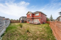 Expansive backyard with a wood privacy fence, a wood-finish deck with white railings, and a storage shed - 