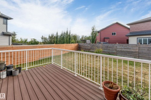 Wood-finish decking with white railing overlooking a fenced yard - 718 Charlesworth Way Sw, Edmonton, AB 