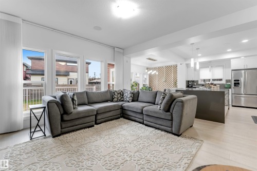 Expansive open-concept living area featuring light wood-finish flooring, recessed lighting, and large windows - 718 Charlesworth Way Sw, Edmonton, AB 