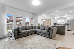 Expansive open-concept living area featuring light wood-finish flooring, recessed lighting, and large windows - 