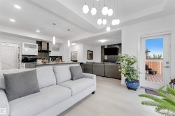 Open-concept living area featuring light wood-finish flooring, recessed lighting, and a modern chandelier - 