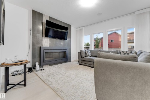 Integrated linear fireplace with a dark-toned tile surround extending to the ceiling - 718 Charlesworth Way Sw, Edmonton, AB 