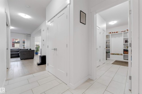 White tile flooring, built-in shelving, recessed lighting, white doors with brushed nickel hardware, and wood-finish flooring - 718 Charlesworth Way Sw, Edmonton, AB 