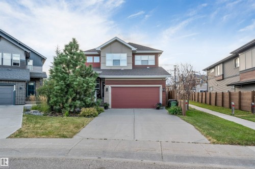 Two-story residence featuring a two-car garage, concrete driveway, and mature front landscaping - 718 Charlesworth Way Sw, Edmonton, AB 