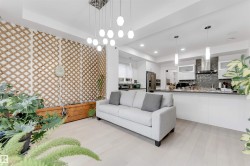 Open-concept living area with light wood-finish flooring, a contemporary multi-bulb chandelier, and a built-in lattice wall feature with a planter - 