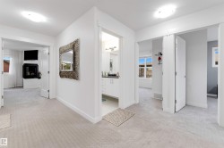 Recessed fireplace with hearth, white built-in cabinetry, light-toned carpeting, and multiple doorways - 