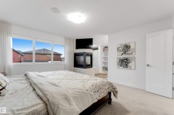 Expansive window with white trim, built-in fireplace, recessed ceiling speaker, white interior door with modern hardware, and light-colored carpet flooring - 