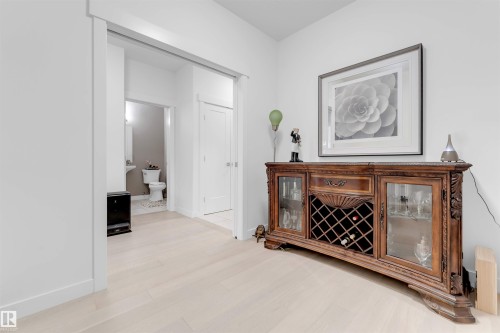 Light wood-finish flooring throughout, modern white walls, and a built-in pocket door - 718 Charlesworth Way Sw, Edmonton, AB 