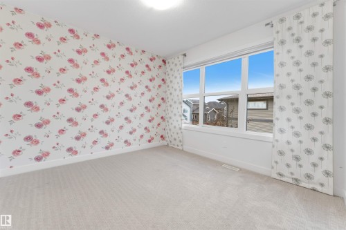Light-toned carpeting, white trim, and a large window providing ample natural illumination - 718 Charlesworth Way Sw, Edmonton, AB 