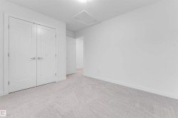 White interior with light grey patterned carpet, featuring a flush mount ceiling light and white double doors with brushed nickel hardware - 
