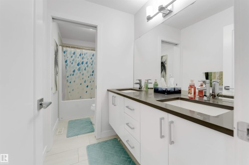 Dual vanity with integrated sinks, modern flat-panel cabinetry, and a full-width mirror - 718 Charlesworth Way Sw, Edmonton, AB 