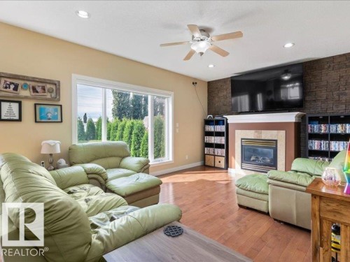 Hardwood-finish flooring, recessed lighting, ceiling fan, wide window, and a stone-accented fireplace with a mantel - 496 Ravine Court, Devon, AB 
