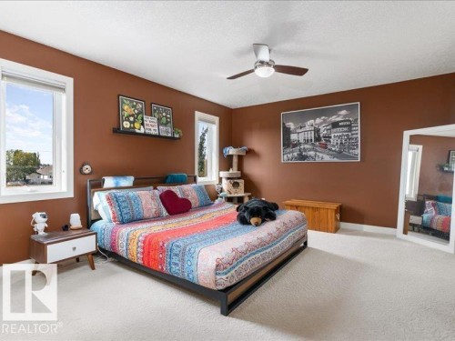 Spacious room featuring multiple windows, a ceiling fan with integrated lighting, and light-colored carpeting - 496 Ravine Court, Devon, AB 