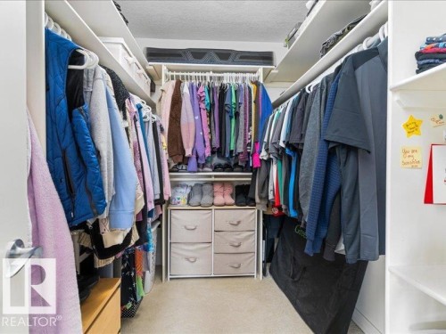 Built-in closet system featuring multiple hanging rods and integrated shelving - 496 Ravine Court, Devon, AB 