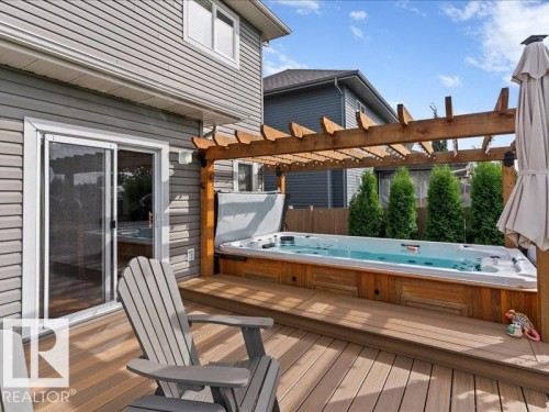 Expansive deck with built-in swim spa, wood pergola, and direct access through a sliding glass door - 496 Ravine Court, Devon, AB 