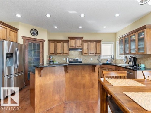Wood-finish flooring, recessed lighting, wood cabinetry, dark countertops, and stainless steel appliances - 496 Ravine Court, Devon, AB 