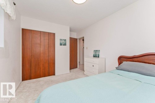 Bedroom featuring light-colored carpeting, white walls, a flush-mount ceiling light, and a window with a sheer curtain - 11415 56 Avenue Nw, Edmonton, AB 