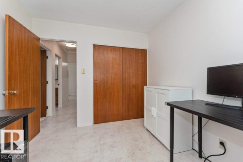 Well-lit room featuring light-colored tile flooring, white walls, and a wood-paneled closet with bi-fold doors - 11415 56 Avenue Nw, Edmonton, AB 